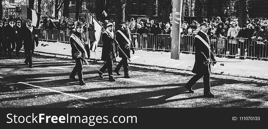 Men Walking On Streets Carrying Flag During Parade In Grayscale Photo