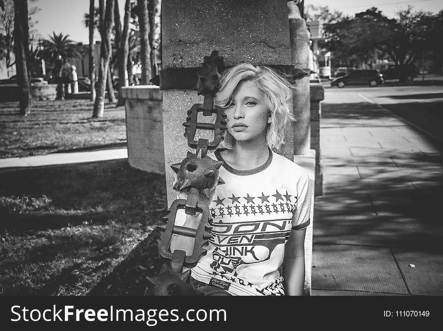 Female Leaning on Gray Concrete Post Grayscale Photo