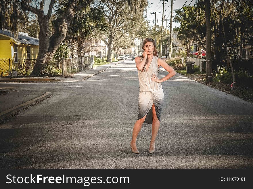 Woman Wearing Grey and Beige Dress Standing on Center of Street