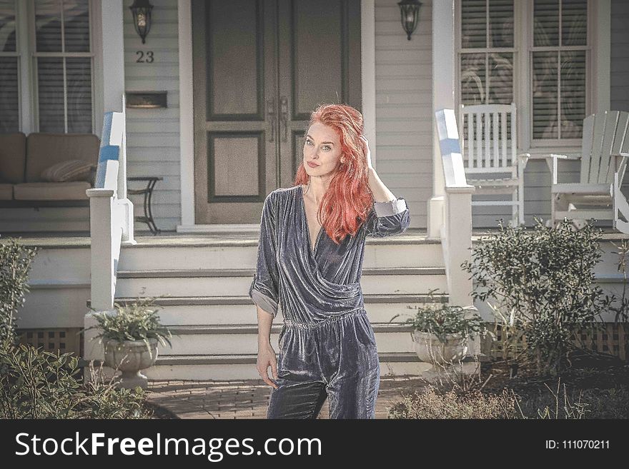 Woman Wearing Gray Peplum Elbow-sleeved Jumpsuit Standing in Front of House