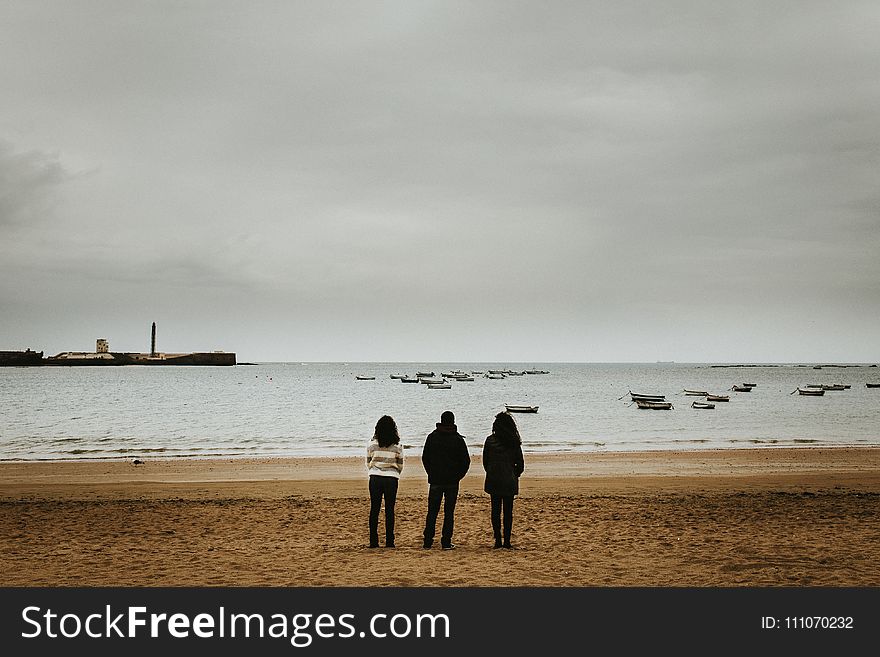 Three Person Standing Near the Seashore