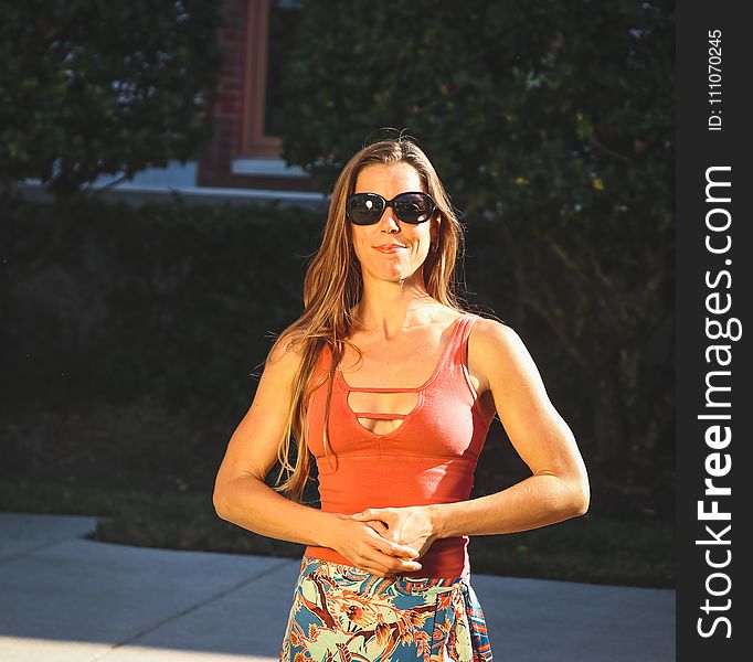 Woman Wearing Orange Strappy Neckline Tank Top and Blue, White, and Orange Floral Skirt