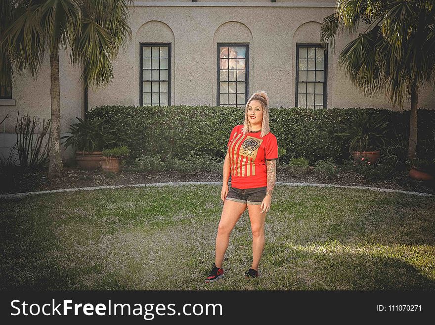 Woman Standing on Grass Field in Front of House