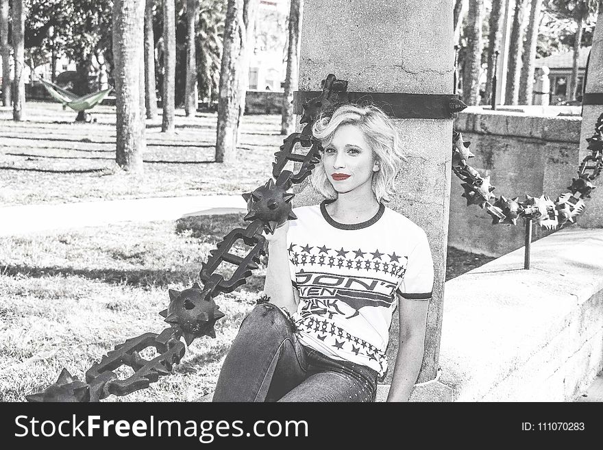 Grayscale Picture Of Woman Sitting On Black Post