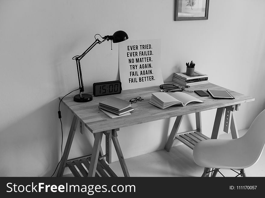 Grayscale Photography Of Desk With Books And Table Lamp