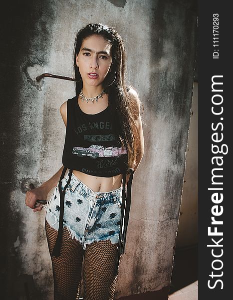 Woman Wearing Black Los Angeles Graphic Crop Top, Blue Denim Stonewashed Cut-off Short Shorts And Black Fishnet Stockings