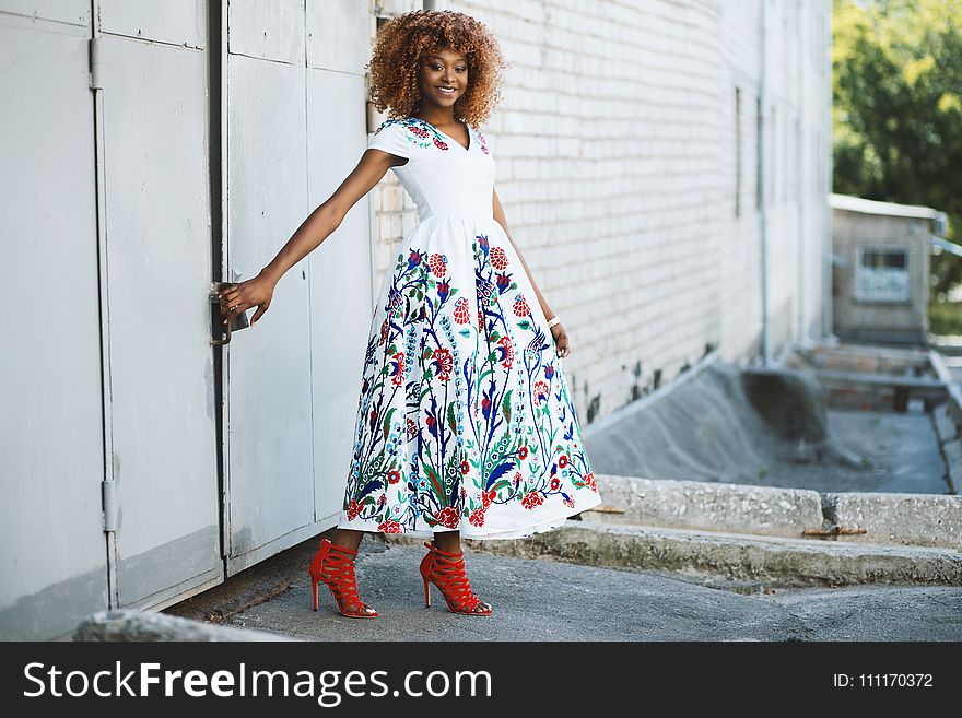 Woman in White and Multicolored Midi Dress Holding Door