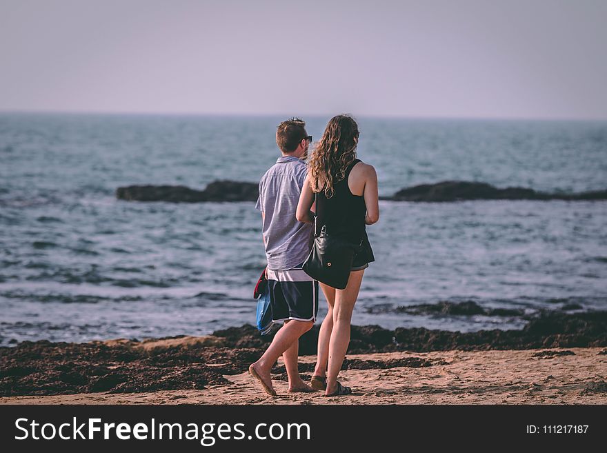 Woman and Man Walking Near Seashore