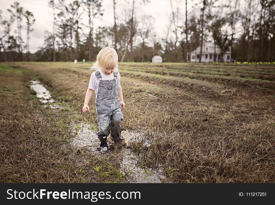 Toddler Wearing Blue Denim Overall Pants Walking on Wet Withered Grass