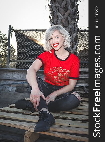 Woman Sit On Pallet Wearing Crew-neck T-shirt And Distressed Black Fitted Jeans