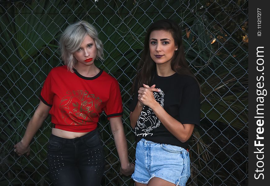 Two Woman Leaning On Fence