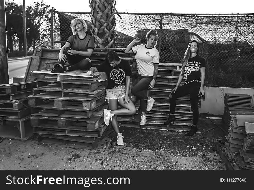 Grayscale Photo of Four Women on Wooden Pallets