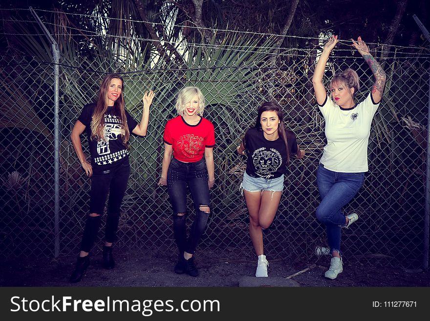 Four Woman Leaning on Chain Link Fence