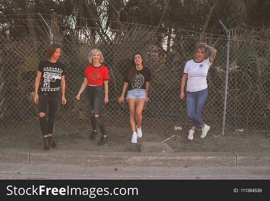 Four Women Standing Against Wire Fence
