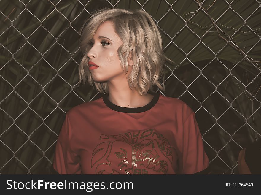Close-Up Photography of a Woman Leaning On Chain Link Fence