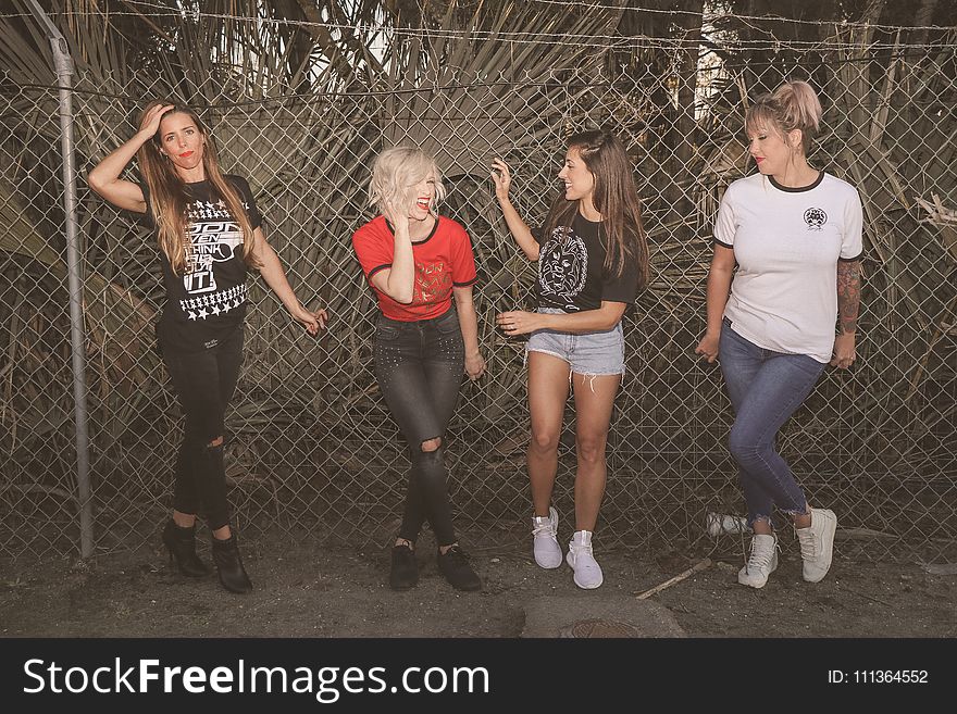 Photo of Four Women Leaning on Chain-link Fence