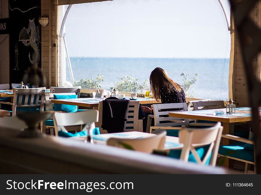 Woman Sitting On Chair With View Of Sea