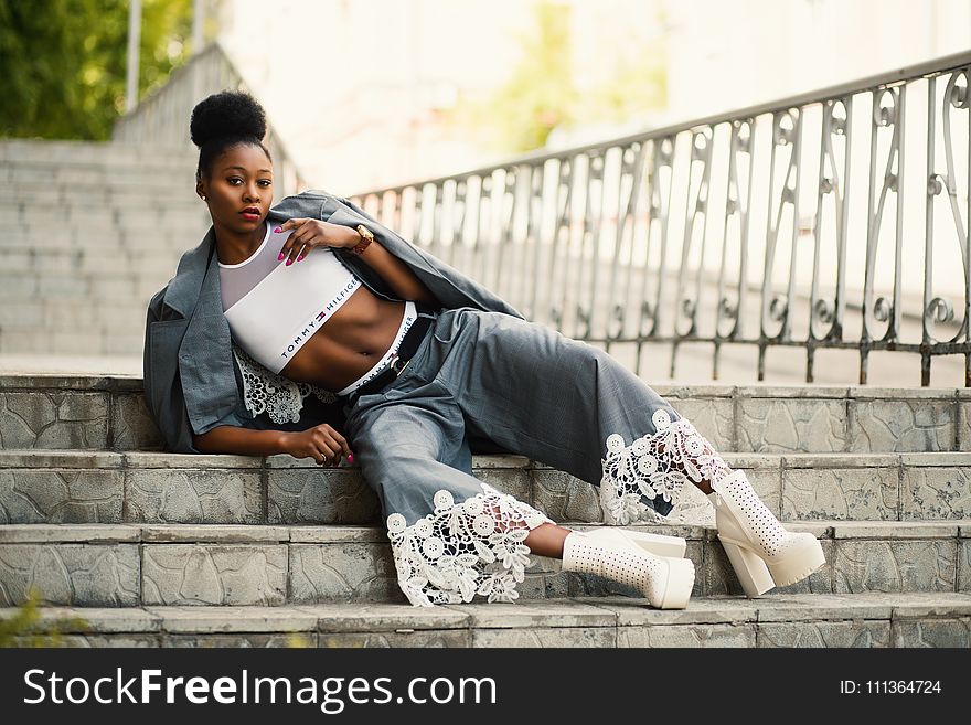 Woman Wearing White Sports Bra and Gray Pants Laying on Stairway