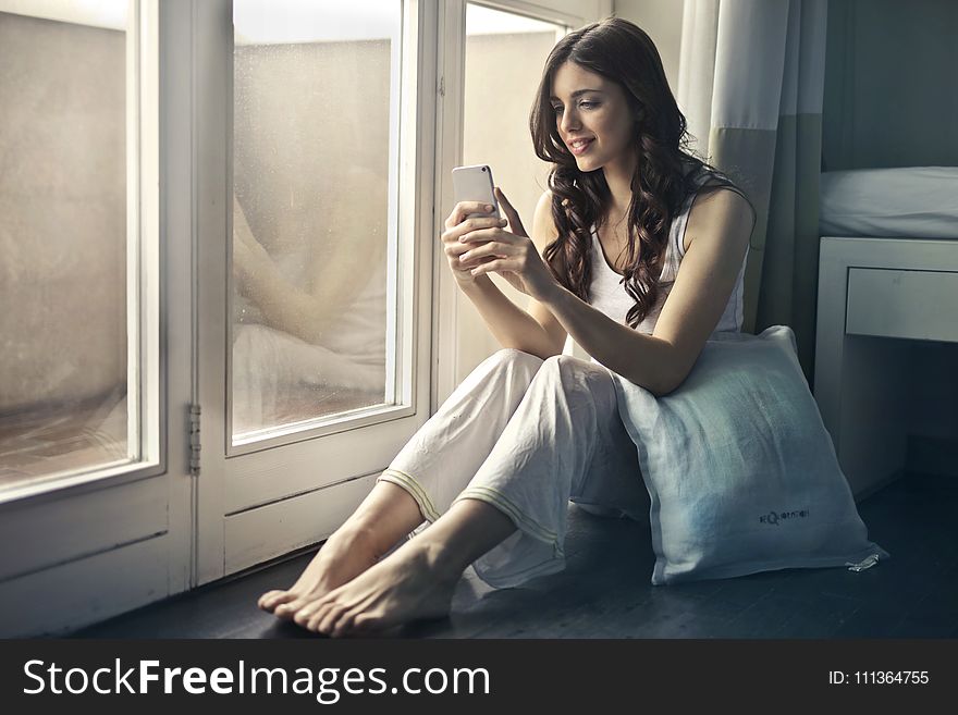 Woman Sitting Beside Window Holding Phone