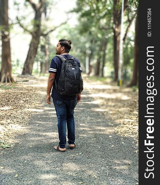 Man in Black and White T-shirt and Blue Denim Jeans Carrying Backpack