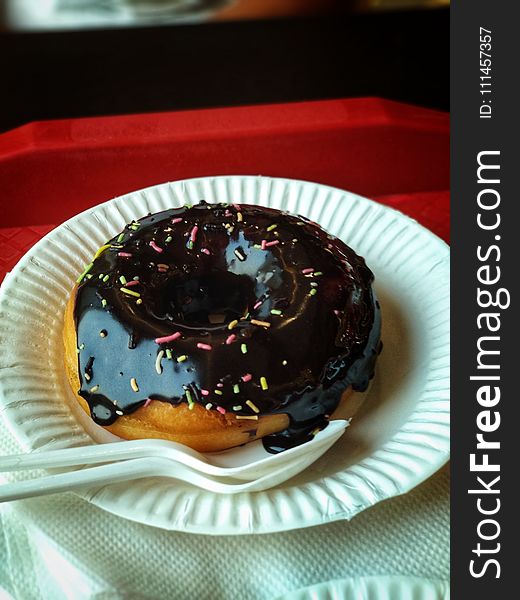 Chocolate Donut Above Round Paper Plate and Plastic Spoon and Fork