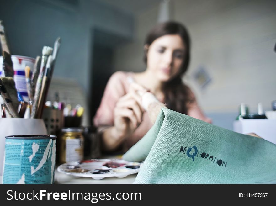 Woman Holding Paper Near Paint Brushes