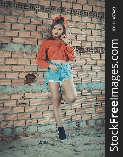 Photo Of Woman Wearing Orange Crop-top Near Brown Concrete Brick Wall