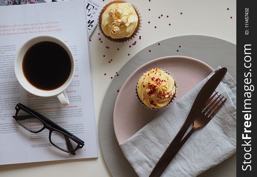 Top-view Photograph of Two Cupcakes, Cup, and Eyeglasses