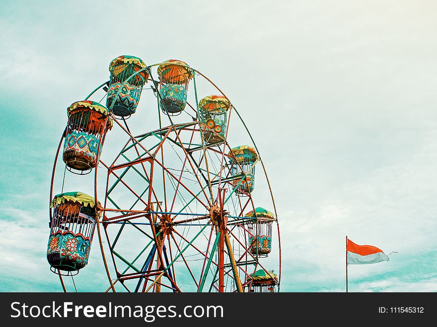 Photography Of Orange Ferris Wheel Beside White And Orange Flag