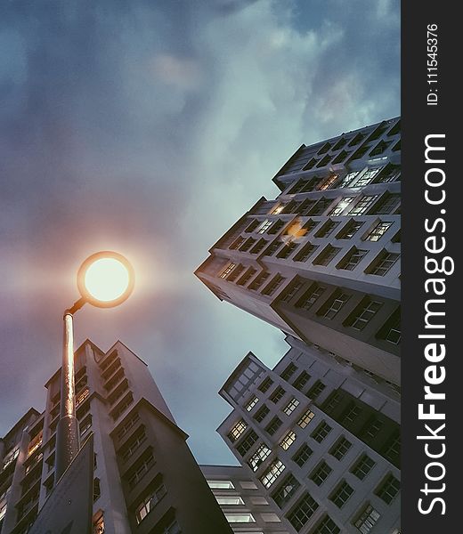 Low Angle Photography of Lamp Post Beside Building Under Cloudy Sky
