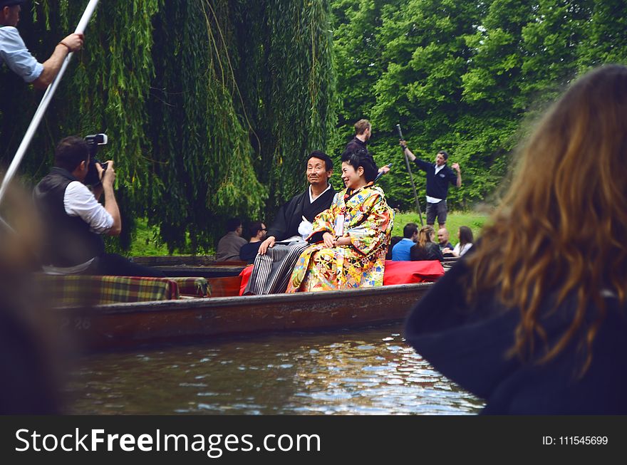 Man and Woman Sitting on Brown Canoe