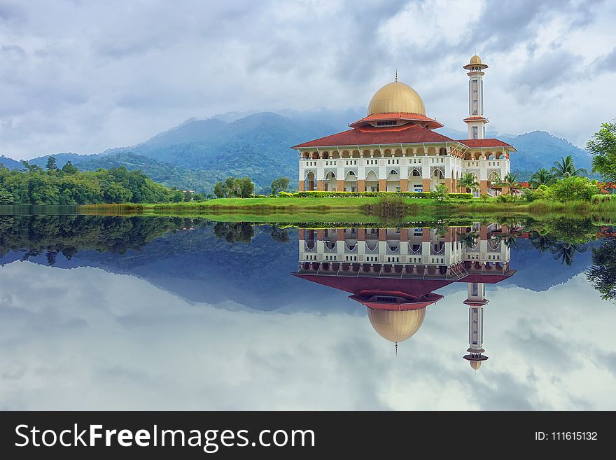 White and Red House Reflecting on Body of Water Under Blue Sky