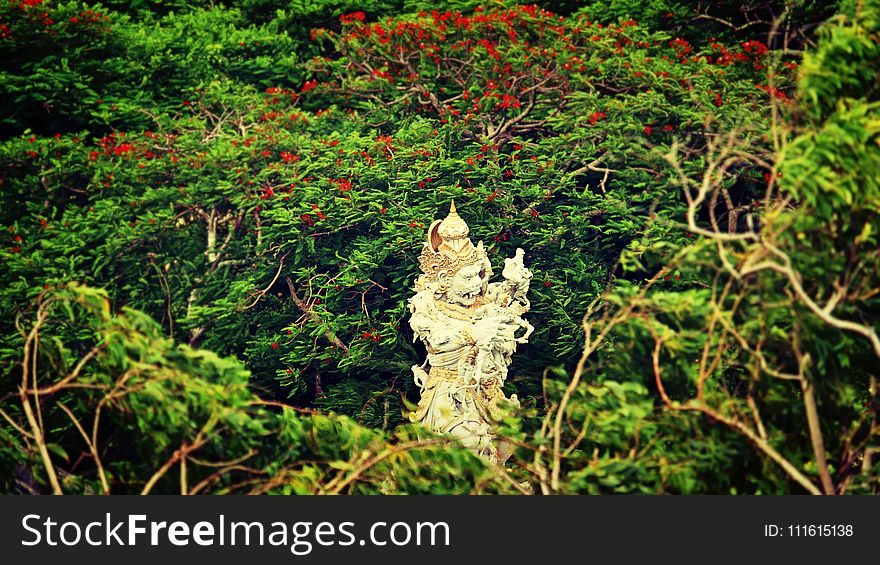 Beige Hindu Statue Surrounded by Trees at Daytime