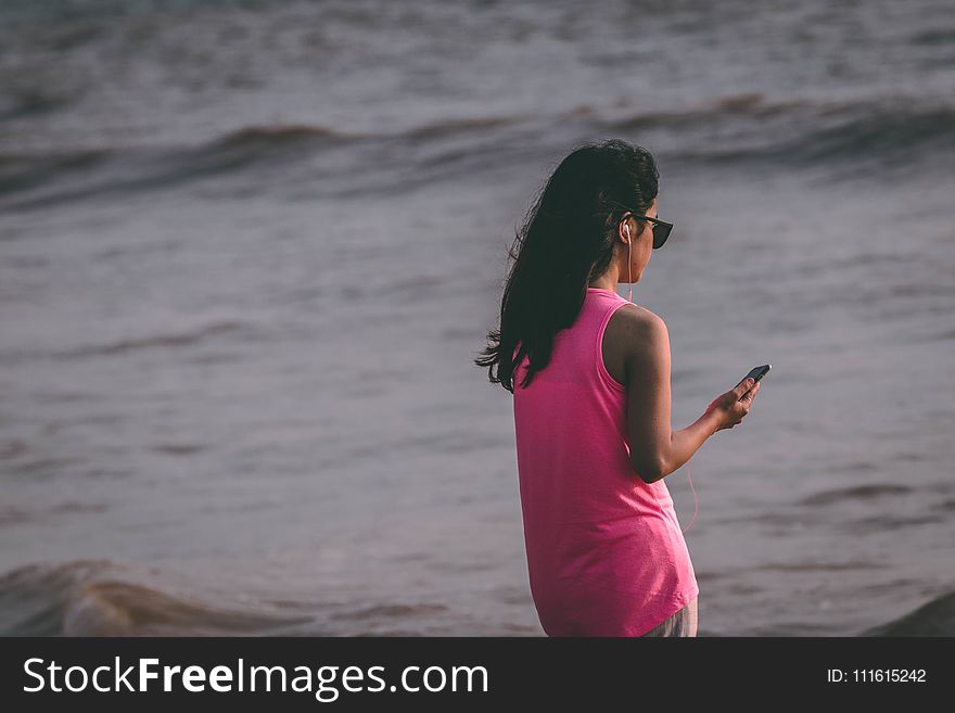 Woman Wearing Pink Tank Top Standing Near Sea Shore