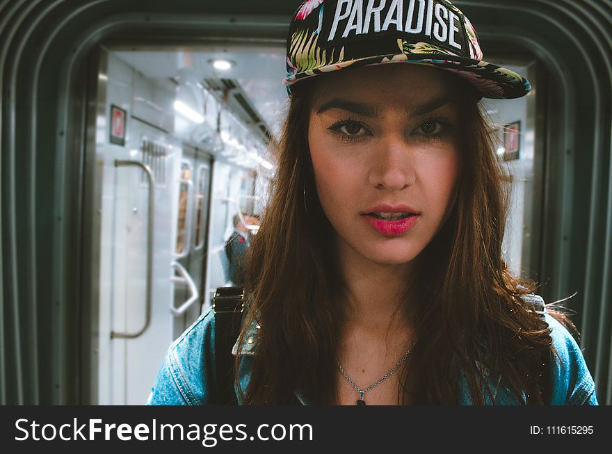 Woman in Blue Top Wearing Black and White Cap With Paradise Text-printed