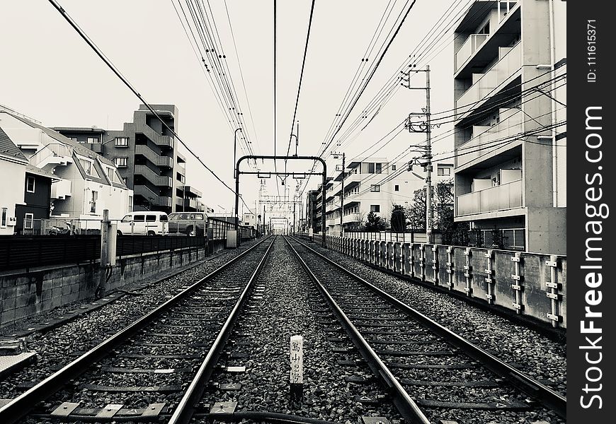 Grayscale Photography Of Train Rail Between Buildings