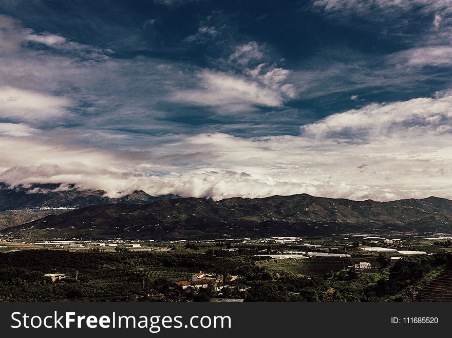 Aerial Photography Of Grass Field Near Mountain Under White Cloudy Sky