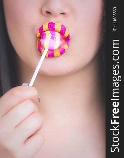 Woman With Yellow and Pink Lipstick Eating LolliPop
