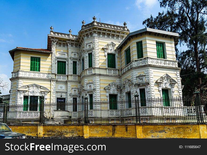 Yellow And White Painted Mansion Near Black Iron Gate