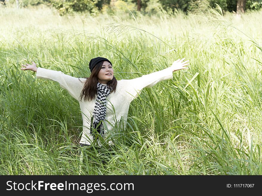 Happy woman enjoy and relax with the nature. Young beautiful woman sitting under the big tree in green forest.