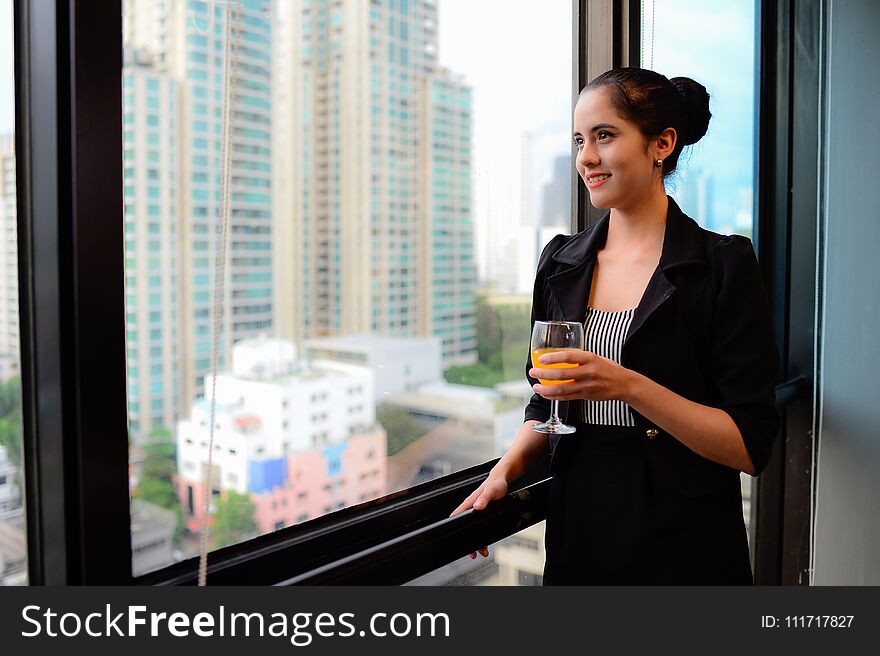 Smile of beautiful business woman at the window with champagne