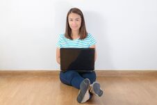 Happy Young Woman Sitting On The Floor With Crossed Legs And Using Laptop Royalty Free Stock Images