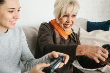 A Young Girl And An Elderly Woman Play Together In A Video Game. Joint Pastime. Family Life. Communication Of The Stock Photo
