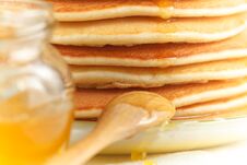 Close Up Of Stack Of Pancake With Pouring Honey, Wooden Spoon And Jar Of Honey Royalty Free Stock Image
