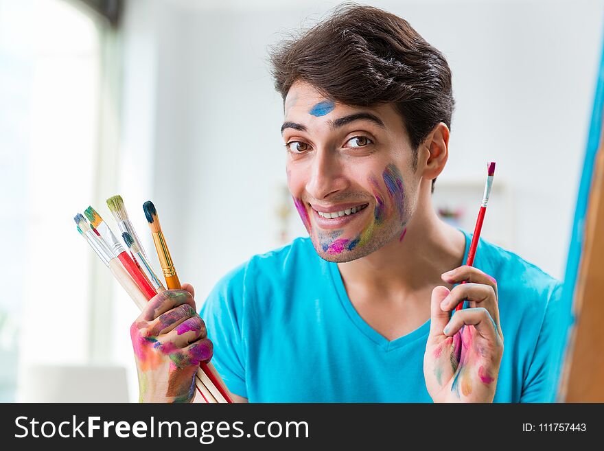 The young funny artist working on new painting in his studio