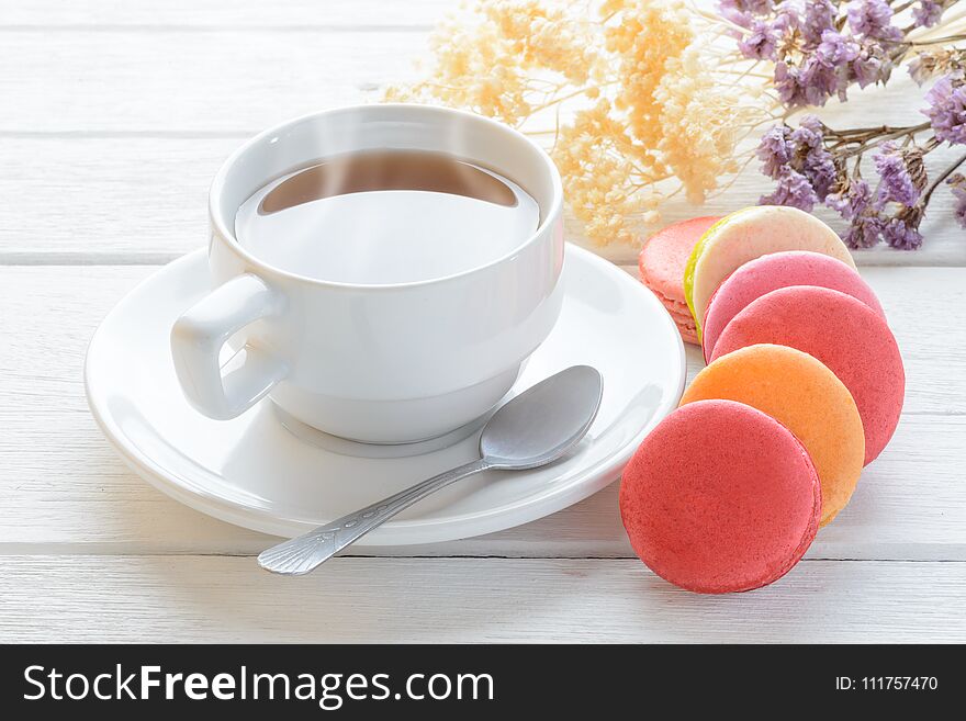 Different types color of macaroons with Cup of hot tea on white