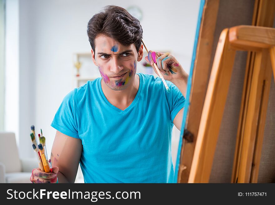 The young funny artist working on new painting in his studio