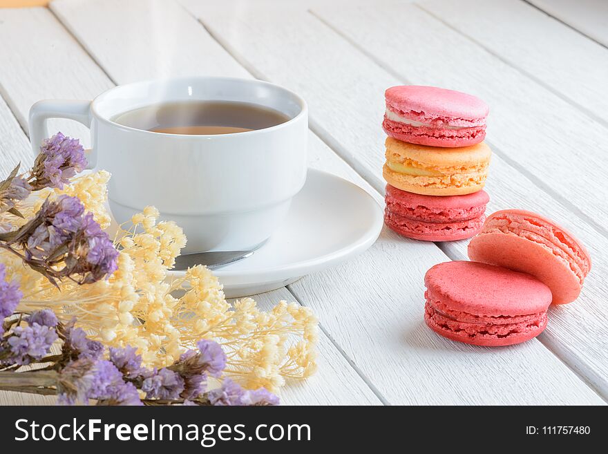 Different types color of macaroons with Cup of hot tea on white