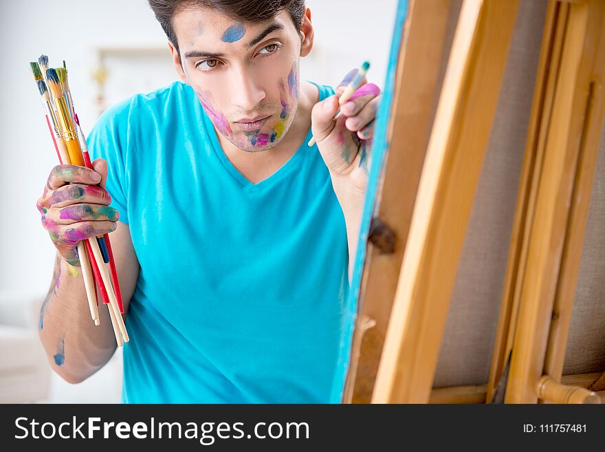 The young funny artist working on new painting in his studio