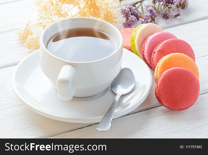 Different types color of macaroons with Cup of hot tea on white